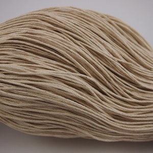 Può includere: Primo piano di un fascio di cordoncino in cotone beige naturale. Il cordoncino è intrecciato strettamente e ha un aspetto morbido e testurizzato.