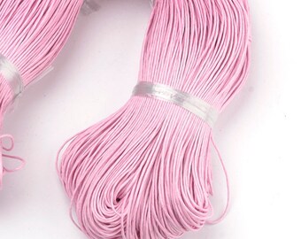 May include: A spool of pink waxed cotton cord. The cord is tightly wound and is ready to be used for crafting projects.