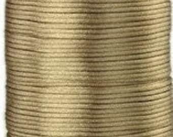 May include: A spool of tan-colored satin cord. The cord is tightly wound, creating a cylindrical shape. The smooth, shiny texture of the cord is visible, suggesting its use in crafts or jewelry making. The spool is made of a light-colored material.