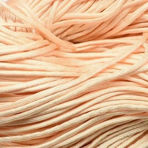 May include: A close-up of a pile of peach-colored cord. The cord is smooth and has a slight sheen.