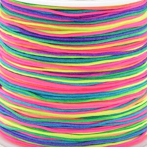 Könnte beinhalten: Eine Spule mit buntem Regenbogen-Schnur, mit Farbtönen in Pink, Grün, Blau und Lila.