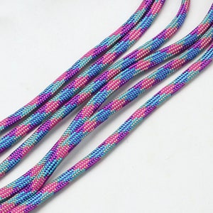Könnte beinhalten: Nahaufnahme von mehreren Strängen bunten Seils mit einem pinkfarbenen, blauen und silbernen Streifenmuster.