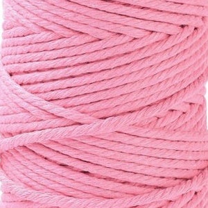 Puede incluir: Primer plano de una bobina de cuerda de algodón rosa. La cuerda está bien enrollada, mostrando la textura de los hilos individuales. El color es un rosa suave y claro. Adecuado para varios proyectos de manualidades.