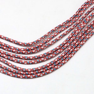 May include: A multi-strand necklace made of red, white and blue cord. The cord has a woven pattern.