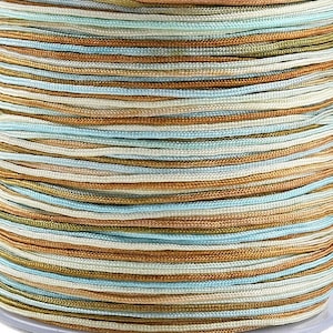 Può includere: Un rocchetto di cordoncino cerato multicolore. Il cordoncino è un mix di colori blu chiaro, beige e oro.