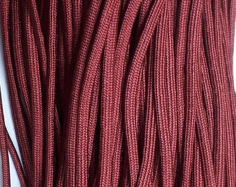 May include: A close-up of a bundle of maroon paracord, a type of strong nylon rope.