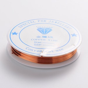 Pode incluir: Um carretel de fio de cobre para fazer joias. O rótulo diz "Special for Jeweller" e "Copper Wire".