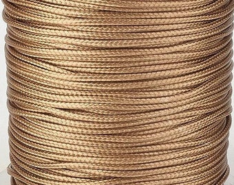 May include: A spool of gold-colored waxed cord. The cord is wound tightly around the spool and has a smooth, shiny finish.