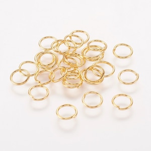 Puede incluir: Un grupo de 25 anillos de salto dorados, un tipo de hallazgo de joyería utilizado para conectar cadenas, cordones y otros componentes de joyería.