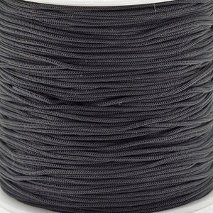May include: A spool of black cord, wound tightly and ready for use in crafting or other projects.
