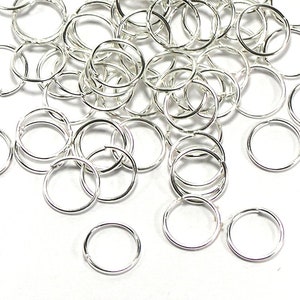 Puede incluir: Un montón de anillas de salto plateadas, un tipo de hallazgo de joyería utilizado para conectar cadenas, cordones y otros componentes de joyería.