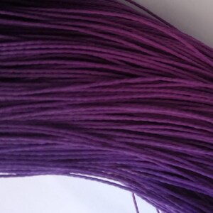Puede incluir: Primer plano de un haz de cordón morado oscuro. Los cordones están muy juntos, creando una superficie texturizada. El color es un tono rico y saturado de morado, con sutiles variaciones de tono. Este cordón es adecuado para varios proyectos de artesanía.