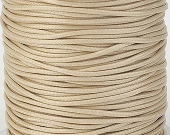 May include: A spool of beige waxed cotton cord. The cord is wound tightly around the spool, creating a smooth, even surface.