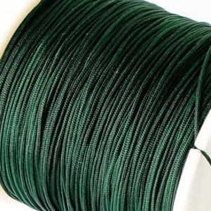 Pode incluir: Um carretel de corda ou barbante verde escuro. A corda está enrolada com firmeza e tem uma textura lisa e uniforme.