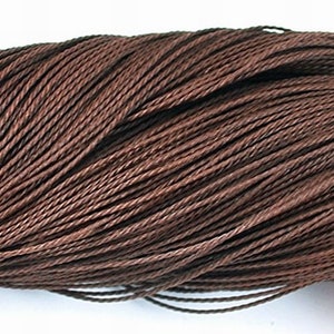Puede incluir: Primer plano de un carrete de cordón encerado marrón. El cordón está enrollado firmemente, mostrando una superficie texturizada. El color es un marrón rico y cálido, adecuado para varios proyectos de manualidades. El cordón parece duradero y flexible, ideal para la creación de joyas y otras manualidades.