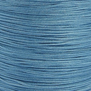 Könnte beinhalten: Nahaufnahme einer Spule hellblauen Nylonschnurs. Die Schnur ist eng gewickelt und zeigt eine strukturierte Oberfläche. Die Farbe ist ein gedämpftes, staubiges Blau, das sich für verschiedene Bastelprojekte eignet. Das Bild hebt die feine, gleichmäßige Textur der Schnur hervor.