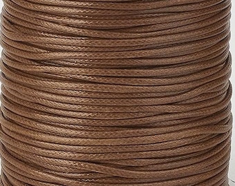 May include: A spool of brown waxed cotton cord. The cord is wound tightly around the spool and is ready to be used for crafting projects.
