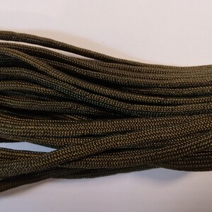 Könnte beinhalten: Nahaufnahme eines Bündels dunkelgrüner Paracord, eine Art von starkem Nylonseil, das oft für Basteln und Outdoor-Aktivitäten verwendet wird.