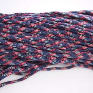 Puede incluir: Primer plano de un carrete de paracord azul, rojo y blanco. El paracord está tejido en un patrón de camuflaje.