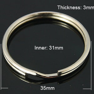 Könnte beinhalten: Silberner Schlüsselring mit einem Innendurchmesser von 31 mm und einer Dicke von 3 mm. Der Ring hat einen Durchmesser von 35 mm.