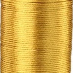 Può includere: Un rocchetto di cordoncino o filo color oro. Il cordoncino è avvolto strettamente attorno al rocchetto.
