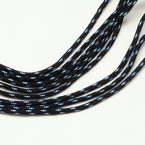 May include: A close-up of black paracord with blue and silver accents. The paracord is arranged in a fan shape.