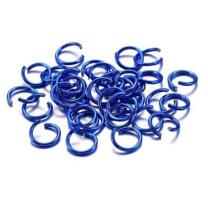 Op de afbeelding: Een verzameling kleine, ronde, open buigringen in een levendige blauwe kleur. Elke individuele ring heeft een gladde, metalen afwerking en een enkele snede, ontworpen voor het maken van sieraden en het verbinden van onderdelen.