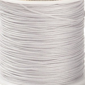 Könnte beinhalten: Eine Spule mit weißem gewachstem Garn. Das Garn ist fest um die Spule gewickelt.