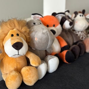 May include: A group of five plush animal toys, including a lion, a hippopotamus, a fox, a cat, and a zebra. The toys are all soft and cuddly, with realistic features.