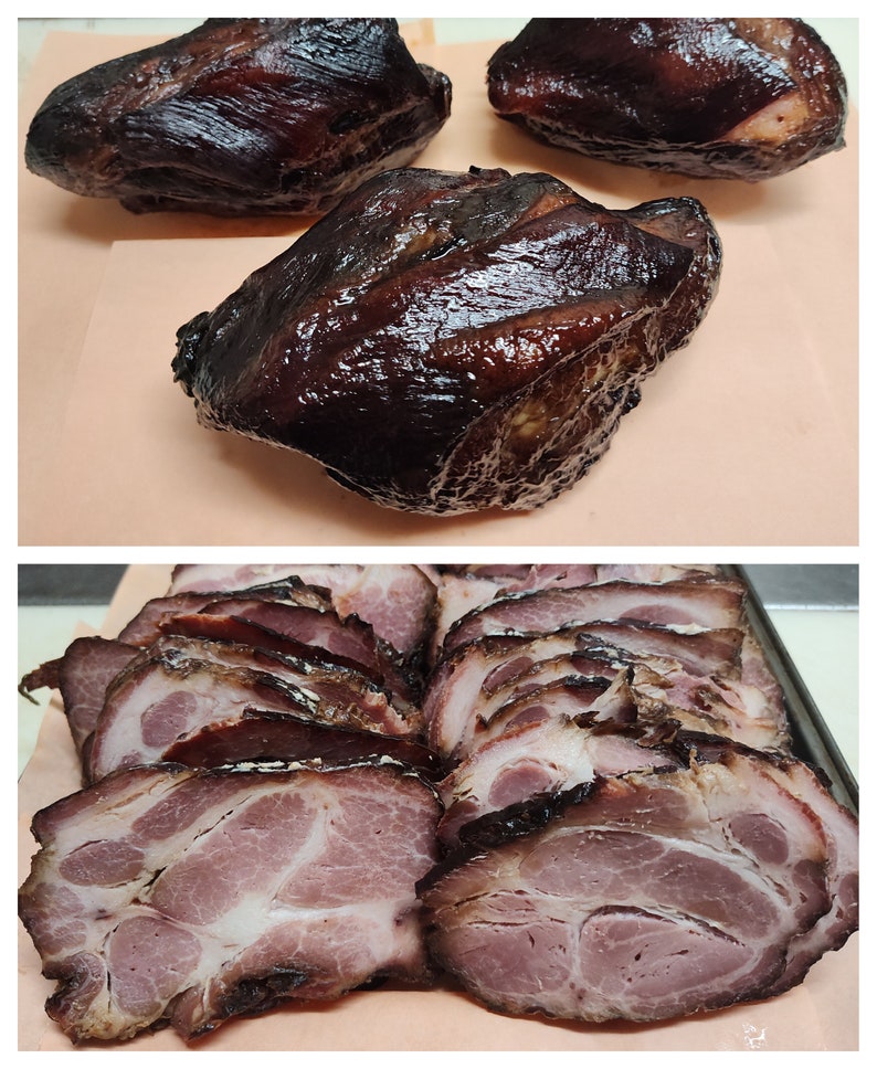 May include: Close-up of smoked pork shoulder, sliced and unsliced. The meat is dark brown and glossy, with a slightly crispy exterior. The slices reveal a pink interior.