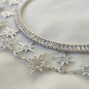 Puede incluir: Dos collares de plata con colgantes en forma de estrella. Los collares est&aacute;n hechos de peque&ntilde;as piedras de circonita c&uacute;bica transparentes. Los colgantes en forma de estrella tambi&eacute;n est&aacute;n cubiertos de piedras de circonita c&uacute;bica.