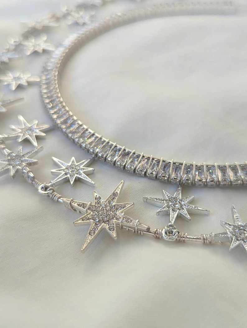 Puede incluir: Dos collares de plata con colgantes en forma de estrella. Los collares est&aacute;n hechos de peque&ntilde;as piedras de circonita c&uacute;bica transparentes. Los colgantes en forma de estrella tambi&eacute;n est&aacute;n cubiertos de piedras de circonita c&uacute;bica.