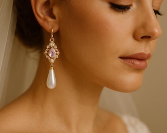 May include: Elegant gold-toned drop earrings. Each earring features a pink gemstone surrounded by small clear crystals, with a large pear-shaped white pearl drop. The earrings are designed for formal occasions.