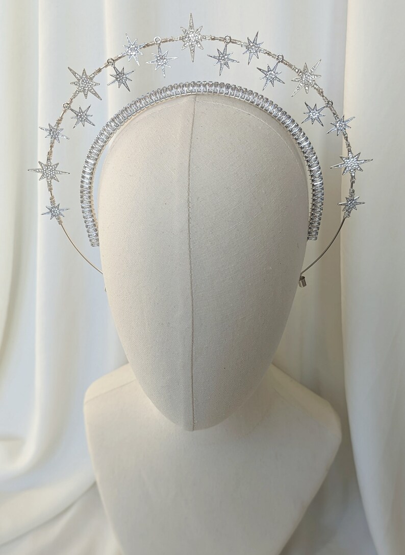 Puede incluir: Una diadema plateada con una doble fila de estrellas brillantes. Las estrellas est&aacute;n hechas de pedrer&iacute;a y est&aacute;n dispuestas en un patr&oacute;n circular.