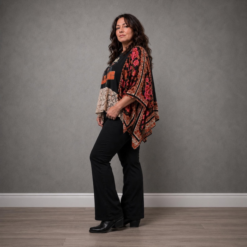 May include: A black graphic t-shirt with orange lettering and a beige lace hem, paired with a black kimono featuring a red and orange floral pattern. The outfit includes solid black flared trousers and black pointed-toe ankle boots.