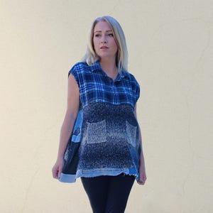 May include: A sleeveless top with a patchwork design. The top features a blue plaid pattern on the upper portion, transitioning to a textured, dark blue fabric with two pockets. The bottom hem is a light blue denim.