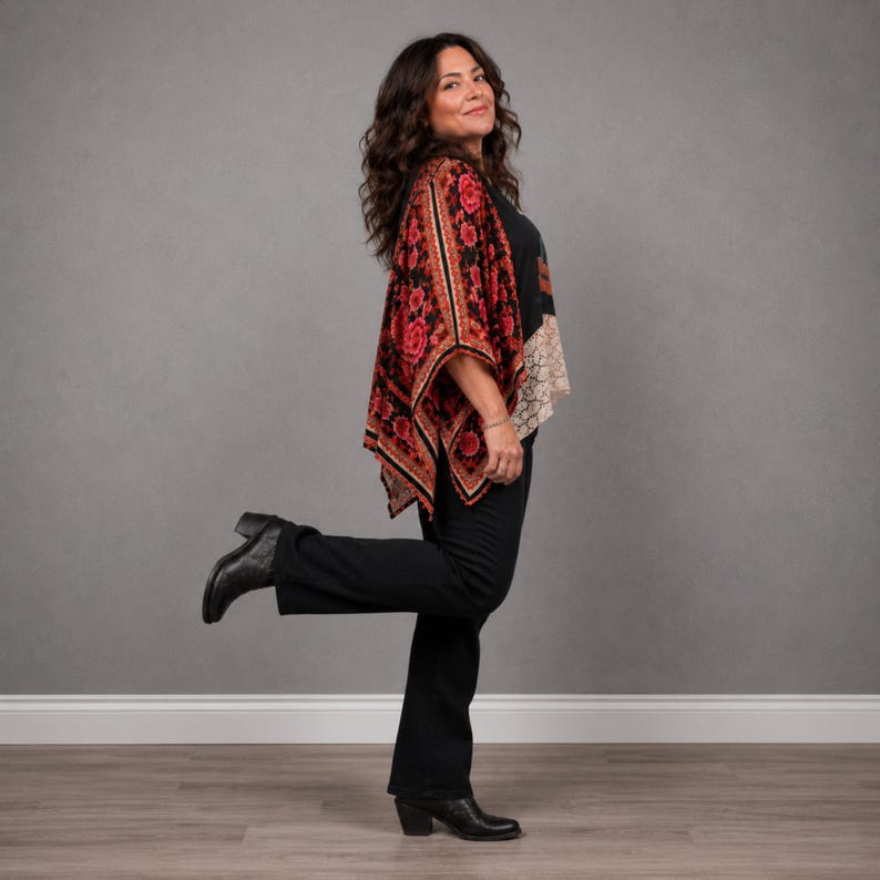 May include: A black top with a red and black floral patterned kimono-style overlay, paired with black trousers and black ankle boots. The kimono features a prominent red rose print with intricate black detailing and a wide, flowing silhouette.
