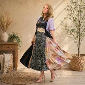 Puede incluir: Un vestido midi patchwork con cuello de cerradura, que combina paneles negros, florales y geométricos. El vestido se lleva con una camiseta de manga corta de color púrpura claro. La modelo lleva sandalias de tacón alto. El vestido es una mezcla de diferentes tejidos.