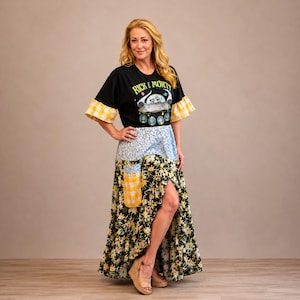 Peut inclure: T-shirt noir avec motif "Rick & Morty", associé à une jupe patchwork avec des motifs floraux, bleus et vichy jaunes. La jupe a une fente haute. Les manches du t-shirt ont une bordure vichy jaune.