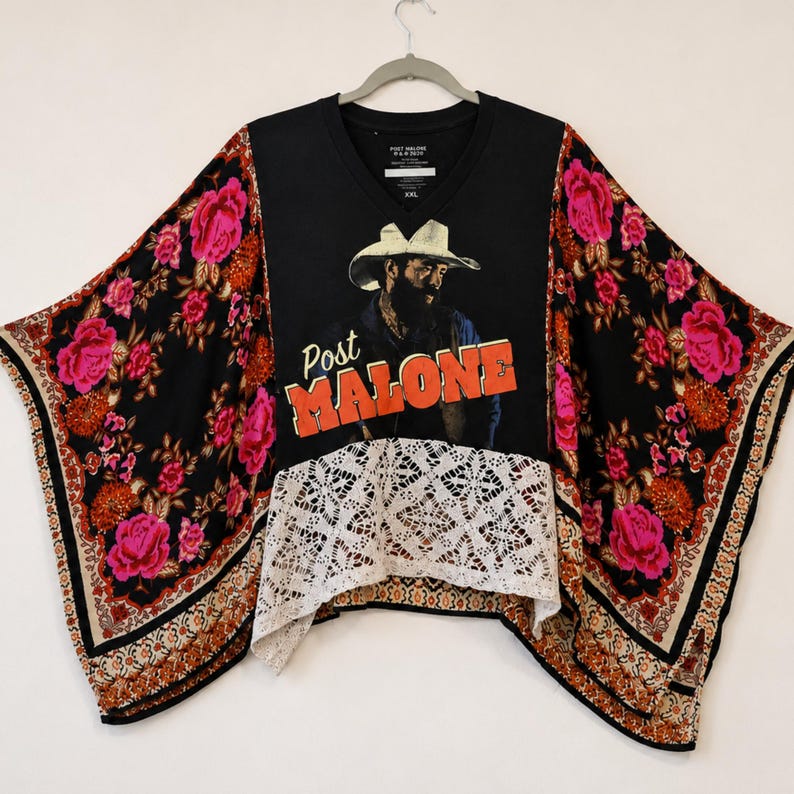May include: A black V-neck top featuring a graphic of a person in a cowboy hat with the text Post MALONE in orange letters. The sleeves and lower back have a black floral pattern with pink roses, and the front hem features white lace trim.