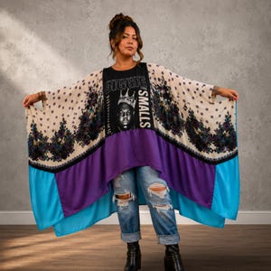 May include: A black graphic t-shirt featuring a portrait of Biggie Smalls with a crown and the text BIGGIE SMALLS, layered under a flowing, wide-sleeved kimono-style cover-up with a cream, purple, and bright blue floral and geometric pattern.
