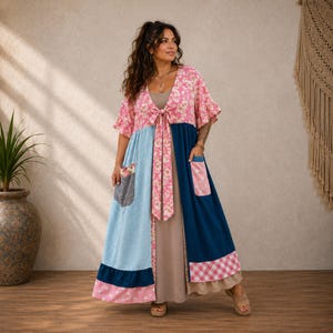 May include: A floor-length dress featuring a beige base layer and a multi-patterned overlay. The overlay has a pink floral bodice with a tie front, a light blue polka dot panel, a dark blue panel, and a pink and white gingham hem with pockets.