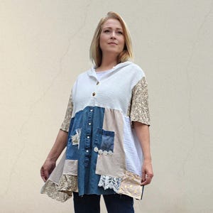以下が含まれることがあります： フード付きネックラインと半袖のパッチワークチュニック。 チュニックは、青、ベージュ、白の色合いのデニム、フローラル、テクスチャードファブリックのミックスが特徴です。 ボタンダウンフロントと装飾的なレースのアクセントがあります。