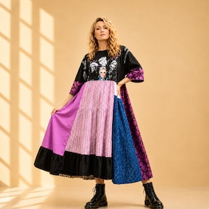 Peut inclure: Une robe patchwork avec un haut noir orné d'un imprimé graphique, une section centrale rayée rose et blanche, et une jupe avec des panneaux violets, bleus et noirs. La robe a des manches courtes avec un motif floral violet et un ourlet noir.