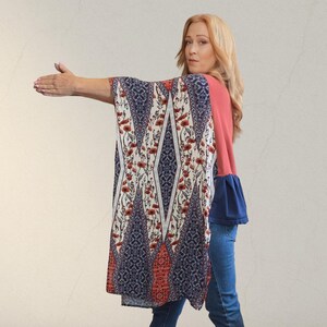 Pu&ograve; includere: Un top stile kimono color corallo e blu navy con un motivo floreale e geometrico. Le maniche sono di colore corallo unito con maniche a campana blu navy. Il top &egrave; abbinato a jeans blu.