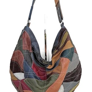 May include: A patchwork leather shoulder bag in a variety of colors including brown, red, blue, and green. The bag has a large, rounded shape with a single shoulder strap. The design features a quilted pattern.