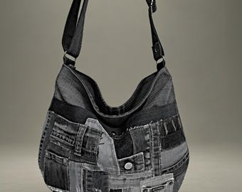 May include: A hobo-style shoulder bag constructed from various shades of dark gray and black denim fabric patches. The bag features a long adjustable strap, visible metal rivets, multiple stitched seams, and a small pocket detail on the front.