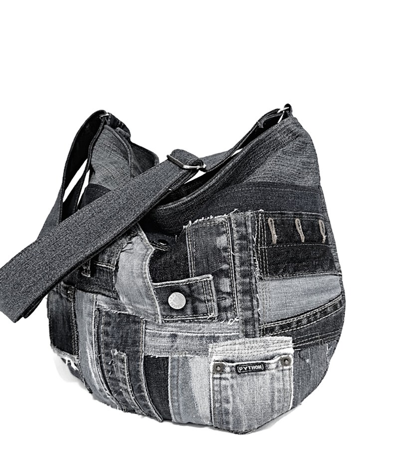 Puede incluir: Un bolso tote de patchwork de mezclilla negra con una correa larga ajustable. El bolso tiene una variedad de parches de mezclilla cosidos juntos, incluyendo algunos con bolsillos y una etiqueta que dice "PYTHON".