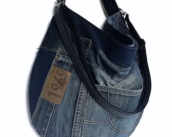 Könnte beinhalten: Eine blaue Jeans-Tragetasche mit einem schwarzen verstellbaren Riemen. Die Tasche ist aus recyceltem Denim gefertigt und hat einen braunen Leder-Patch mit dem Text "1978 s.Oliver" darauf.