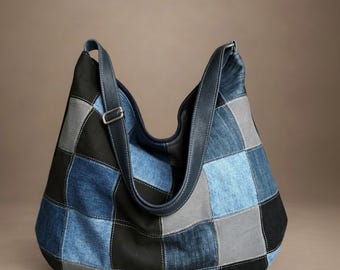 May include: A hobo-style shoulder bag constructed from a patchwork of denim and fabric squares in shades of black, light blue, medium blue, and grey. The bag features a single wide shoulder strap with a silver-toned metal buckle adjustment.